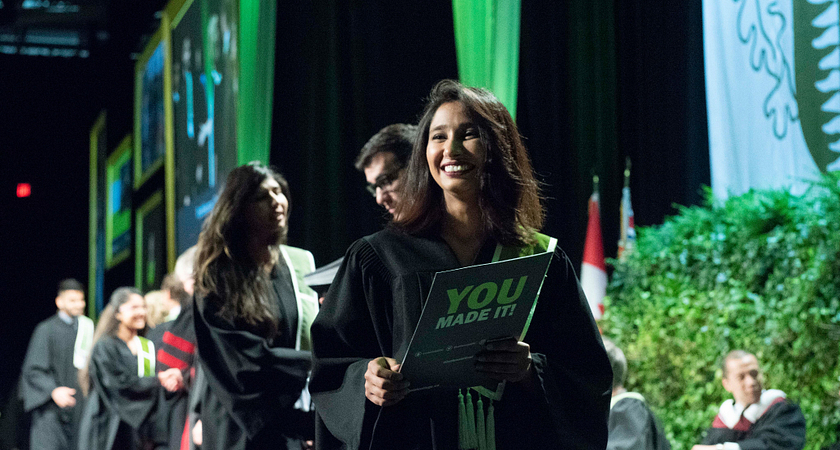 centennial college graduate at their convocation ceremony crossing the stage and smiling